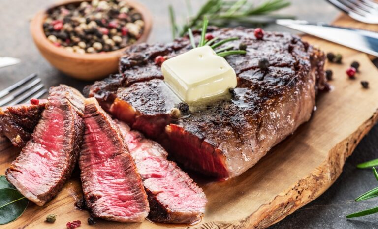 grilled,medium,rare,ribeye,steak,slices,with,melting,butter,on